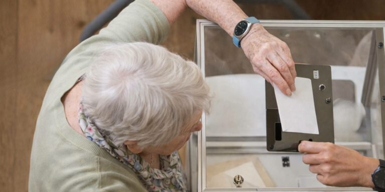 Chez Ange Gardien, nous considérons que le droit de vote ne s’arrête ni avec l’âge, ni avec la fragilité – accompagnement au vote des personnes âgées ou en perte de mobilité Chez Ange Gardien, nous considérons que le droit de vote ne s’arrête ni avec l’âge, ni avec la fragilité - personne âgée en train de voter devant une urne